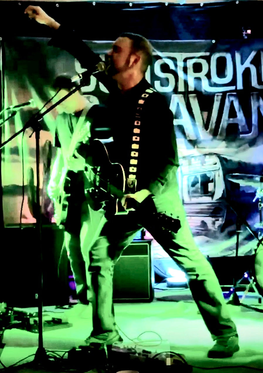 Sunstroke Caravan guitarist under green stage lights